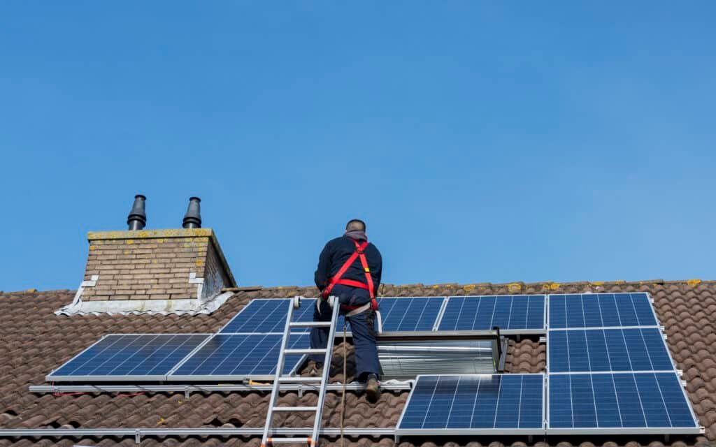 solar panel on roof being installed with man on a ladder